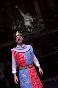 Production photo of Henry with Harfleur Governor on ladder waving white flag high in the background