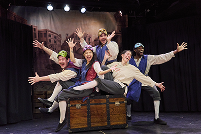 Faction of Fool Commedia Romeo and Juliet: Chorus The "Capulet Cast" sitting on or pushing a trunk, in costume, masks pulled up on the top of their heads, and arms spread in greeting.